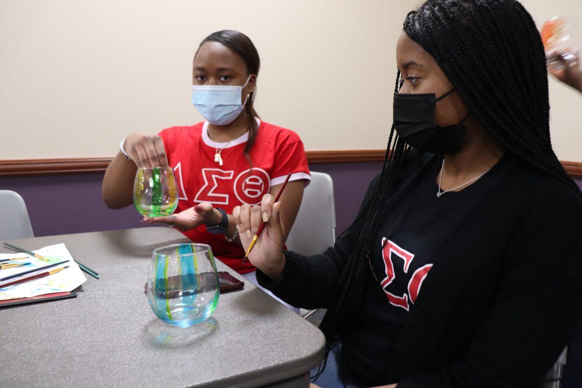 Senior Mackenzie Jordan and Kaley Hale, junior and vice president of Delta Sigma Theta, paint glasses at Delta Sigma Theta’s “World of Creation” event.