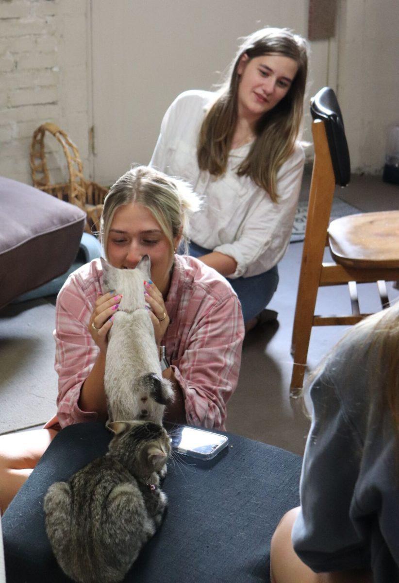 Junior biology major Mattie Neighbors pets a cat while junior music education major Lora Butcher looks over her shoulder.