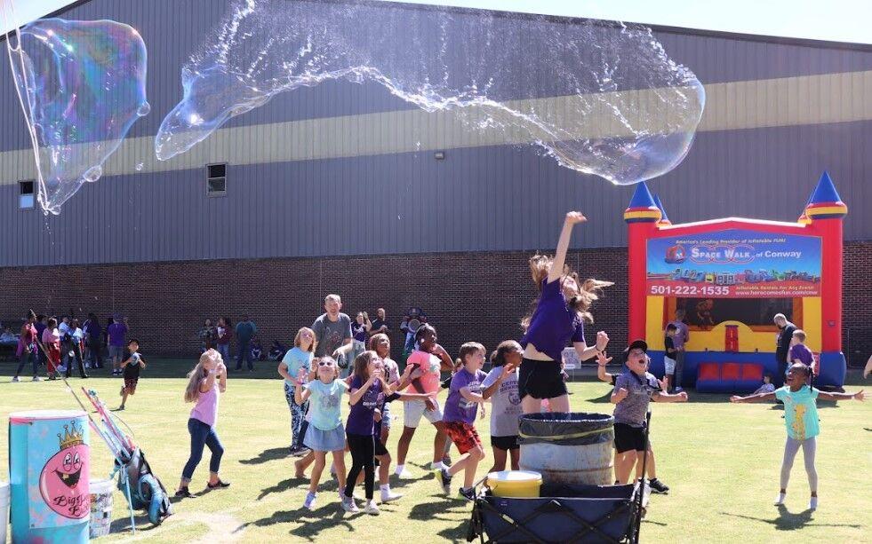 A child jumps up to pop a bubble made by Matt Mattingly, owner of Big Poppa Bubble.