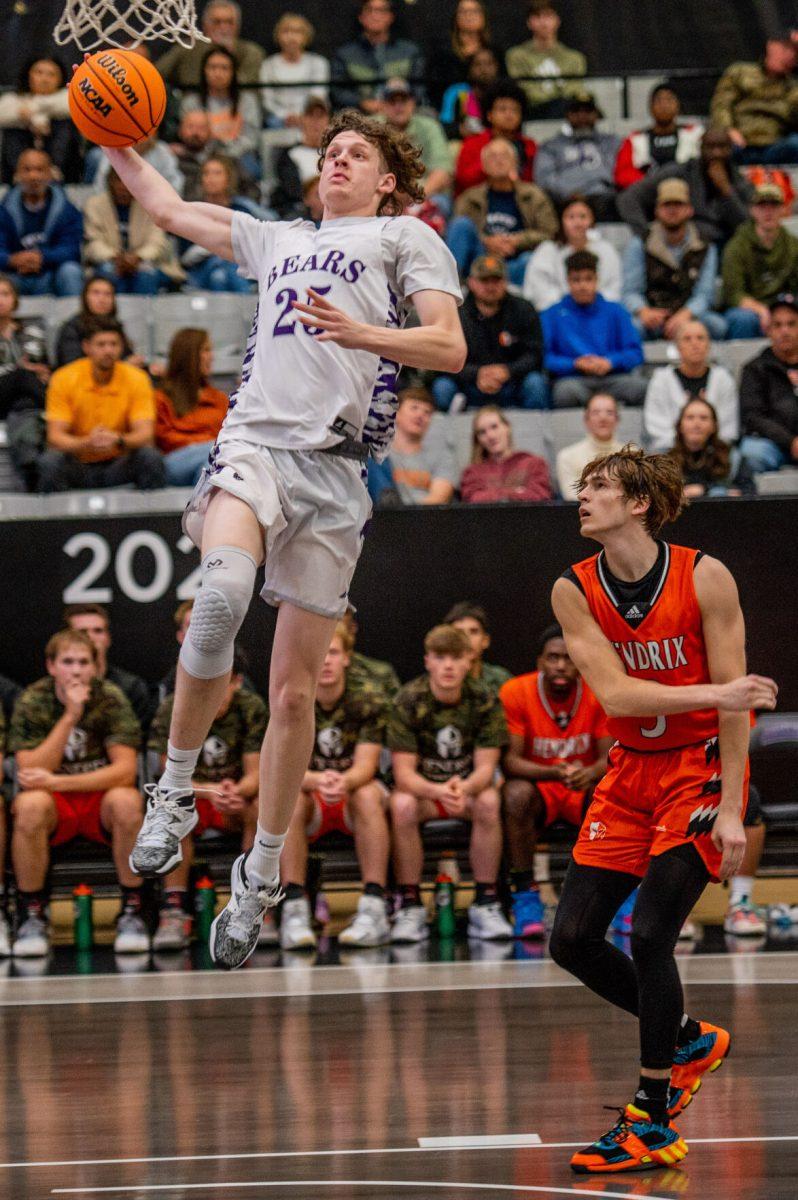 Sophomore guard/forward Elias Cato (left) leaps for a dunk ahead of Hendrix junior guard Jackson Parks.