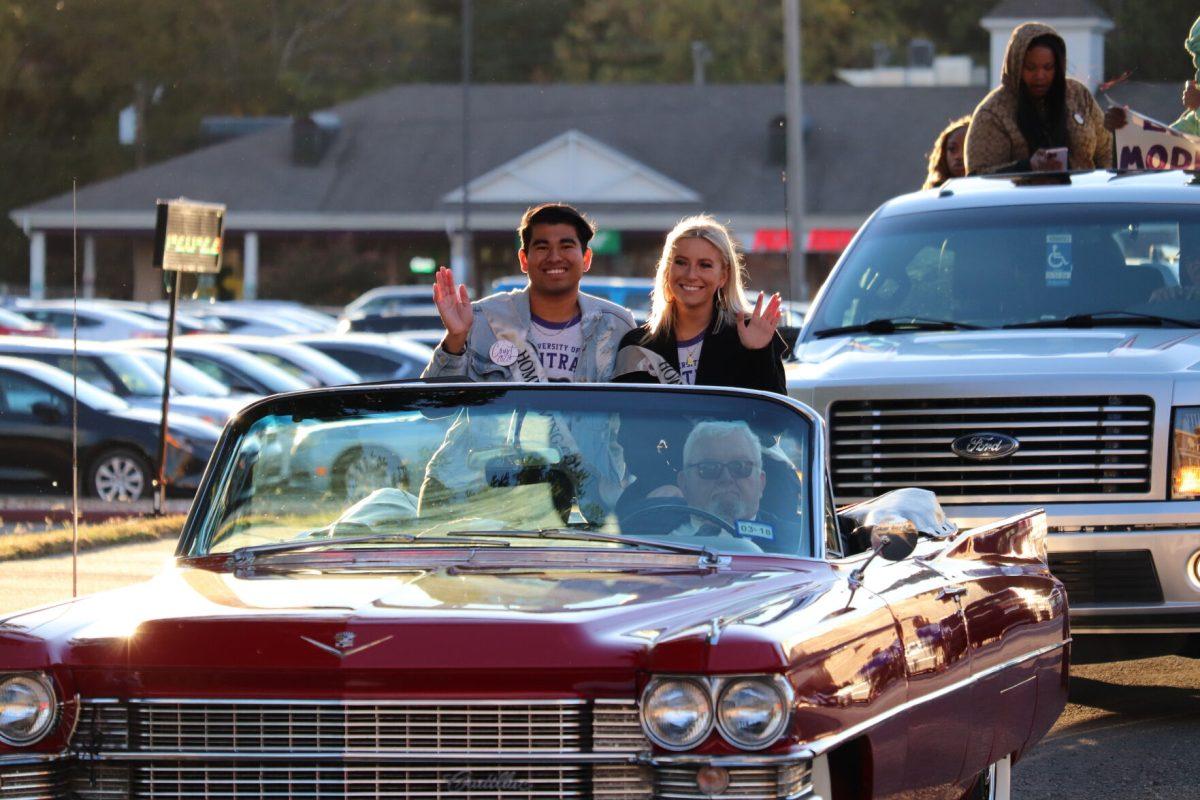 (Left) Ricardo Guevara and (right) Lizzie Langston ride along in the homecoming parade as part of the homecoming court. The parade was held Oct. 25 and started on Western Avenue, went down Bruce Street and circled through campus.
