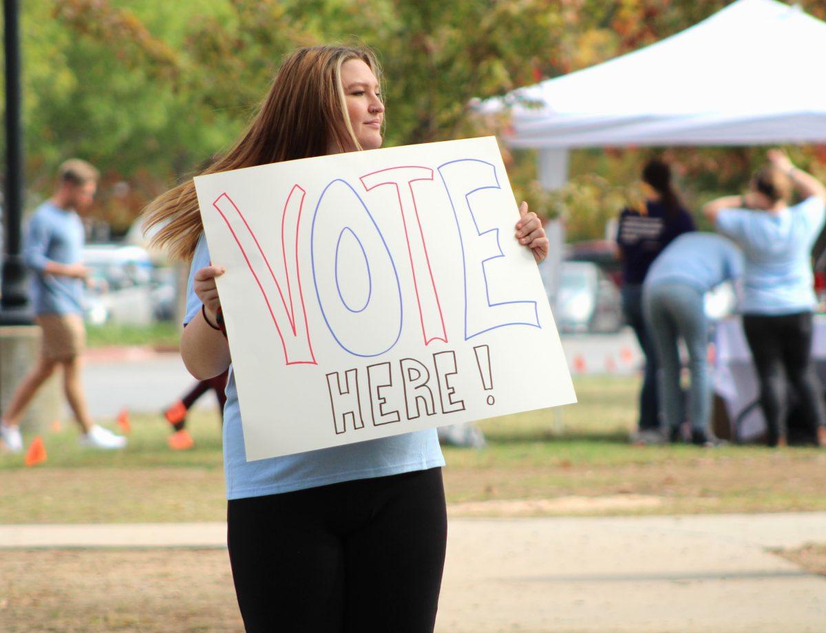 Senior Madison Yarbrough holds a sign to advertise Donaghey Hall’s polling site. Student volunteers held signs for Party at the Polls to encourage student voting and to promote the event.
