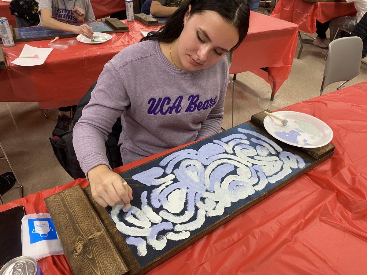 A student paints a handmade coffee board at “Board and Brush Art,” an event hosted by the Student Activities Board in collaboration with Board and Brush, a local creative studio. Students were able to choose between various types of wood coffee boards to paint while sipping on a variety of beverages such as iced coffee, Gatorade and water.