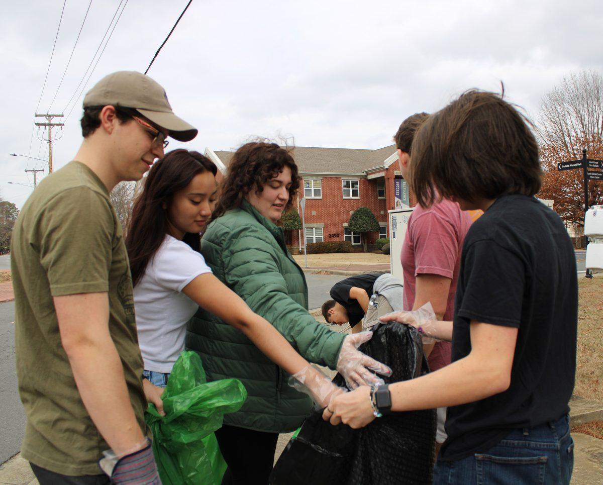 Resident assistant Aiden Barber holds a trash bag open. In addition to bagging trash, the cleanup also focused on recycling education. 