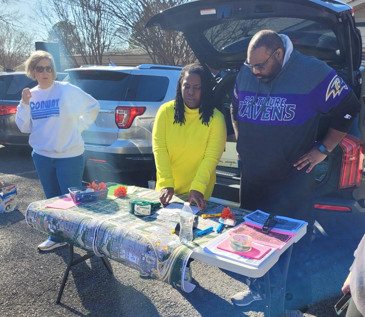 At a table in the Northside Chuch of Christ parking lot, Shanda New, Marilyn Chapman and Jason Chapman work on assigning volunteers areas to canvass. Marilyn is a librarian at CJHS.