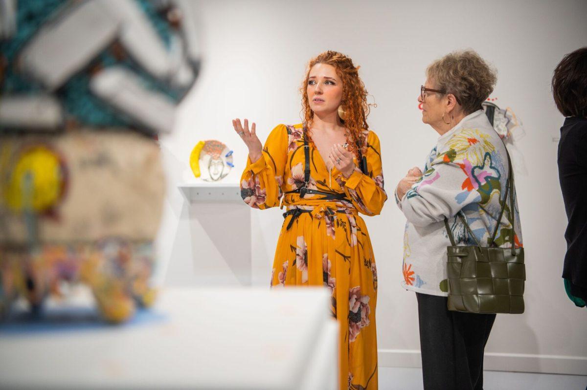 The inaugural alumni artist-in-residence, Anna Wagner, discusses her art with a member of the public at her exhibition’s Feb. 23 reception. Her art collection, “Disorder: A Hard Pill to Swallow,” is at Windgate until March 29.