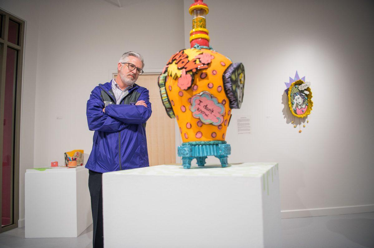 President Houston Davis observes art by Anna Wagner at the exhibit's Feb. 23 reception. Wagner was the first recipient of a $6,500 grant for alumni artists.