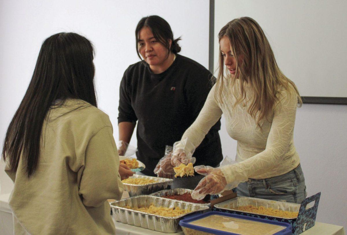 Sigma Kappa sisters serve different types of mac and cheese to hungry attendees.