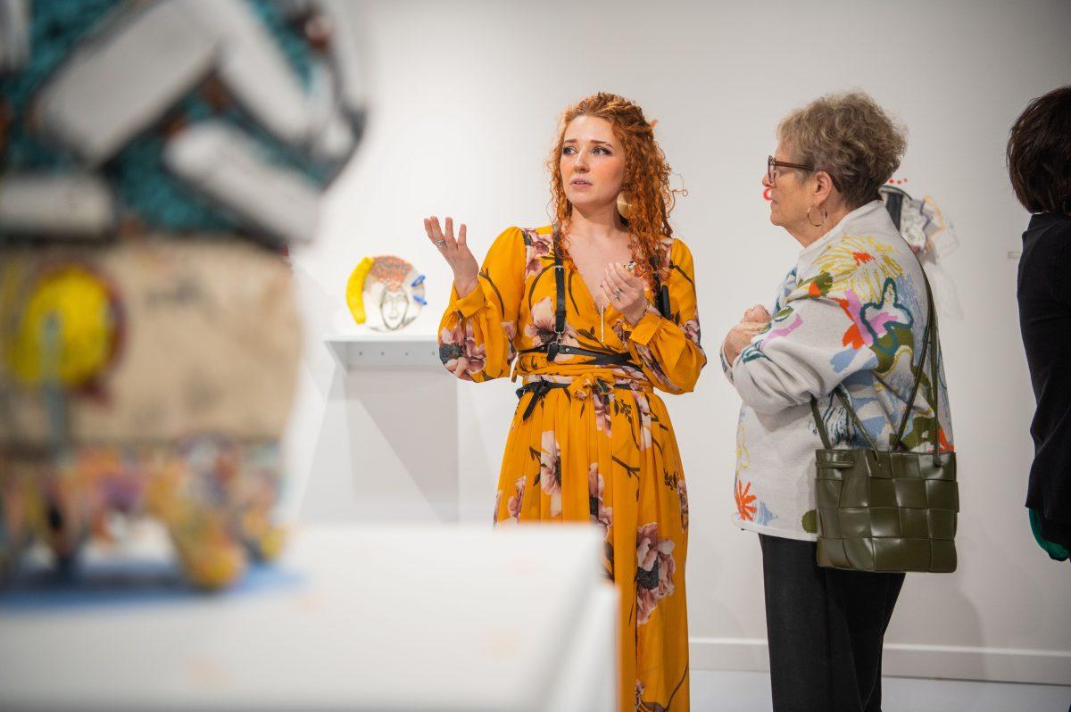 The inaugural alumni artist-in-residence, Anna Wagner, discusses her art with a member of the public at her exhibition’s Feb. 23 reception. Her art collection, “Disorder: A Hard Pill to Swallow,” is at Windgate until March 29.