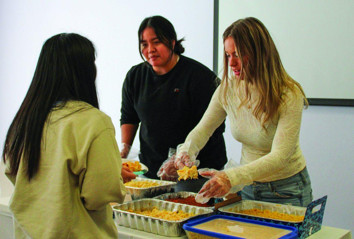 Sigma Kappa sisters serve different types of mac and cheese to hungry attendees.