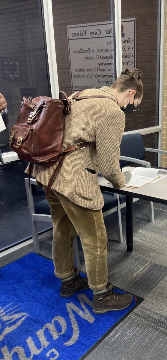Hypatia Meraviglia puts their name on the March 14 meeting's sign-in sheet. The meeting, held at the Conway Public Schools administration building at 2220 Prince St., was nearly full, and had multiple police officers monitoring the entrance.