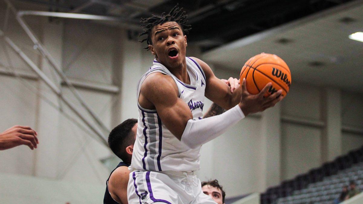 (Top) Junior guard Camren Hunter rushes toward the net for a layup againstan opposing team. During the 2022-23 season Hunter played for a total of 816 minutes and scored a total of 401 points.