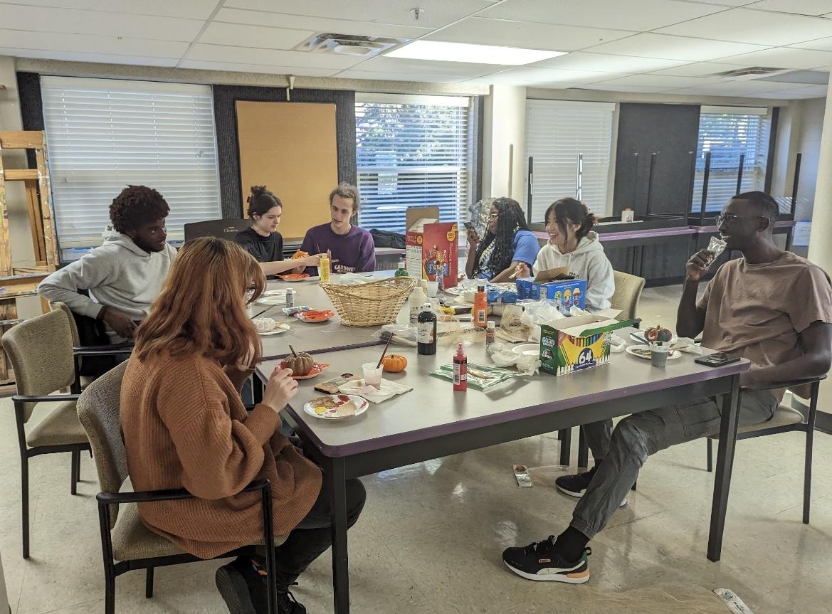 Several students gather around a table to paint miniature pumpkins and chat. The event aimed to give students a way to wind down before fall break Oct. 17. 
