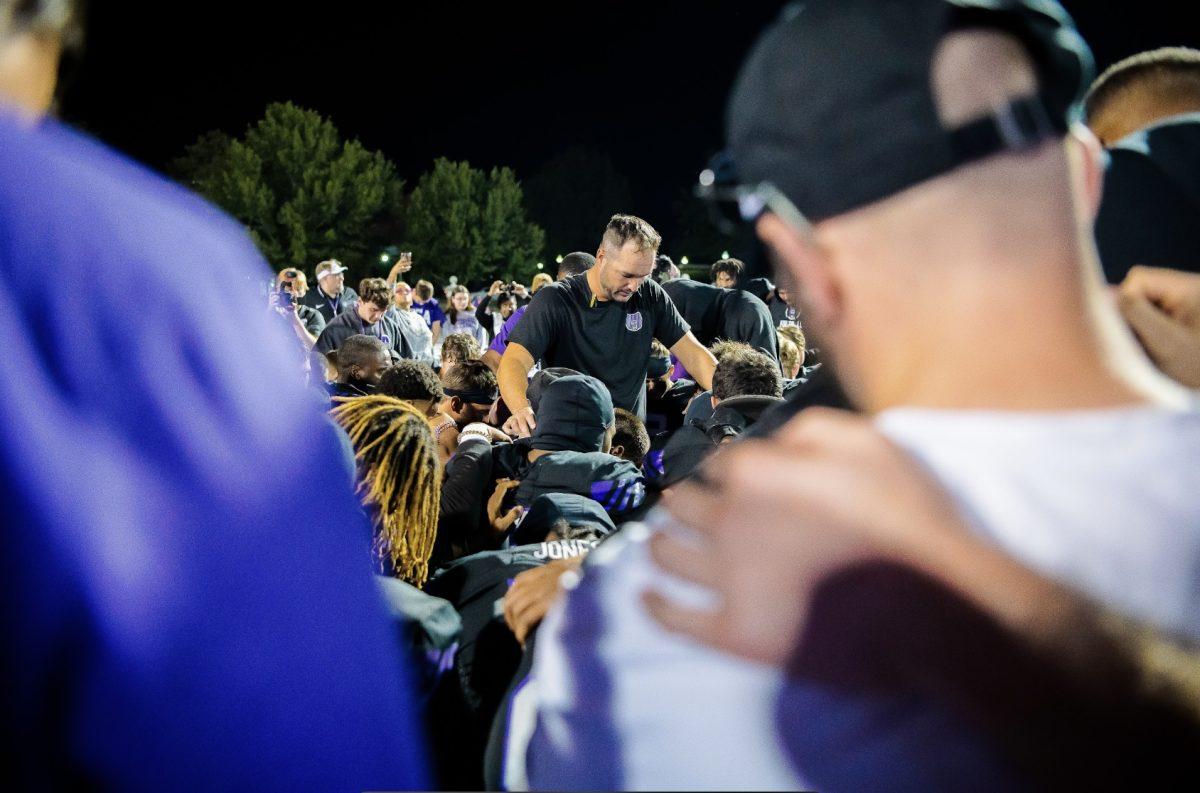 Coach Nathan Brown prays with the team. The Bears won the game 38-33. 