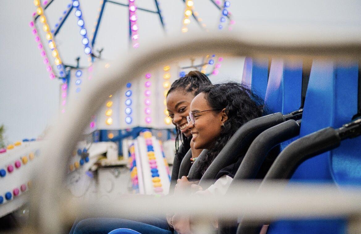 Students smile as they prepare to take a trip on a carnival ride.