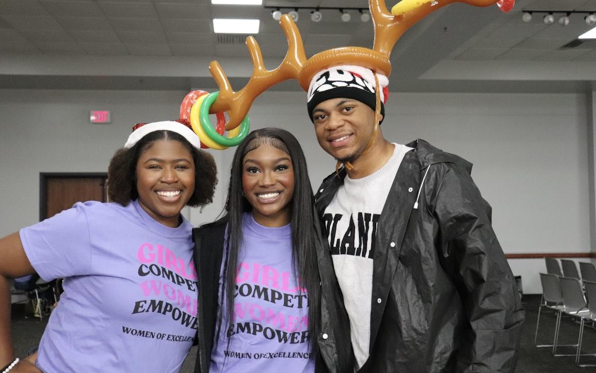 Women of Excellence and Minority Mentorship Program members take photos with holiday props. 