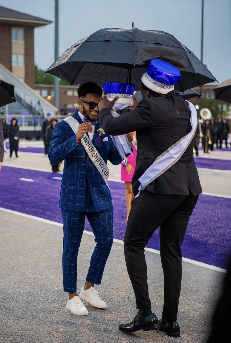 Wilson smiles as last year's homecoming king; Nelson Omolo, places the crown on him.