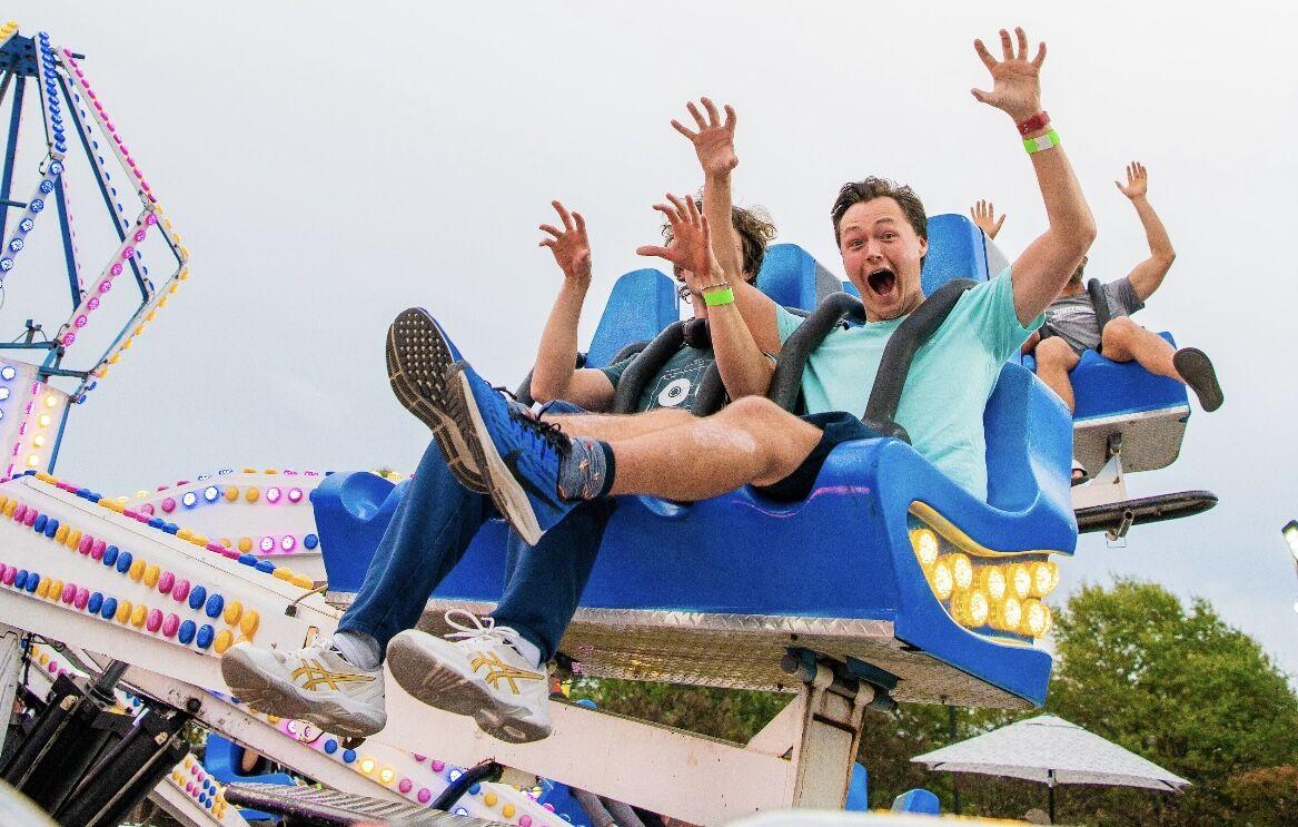 Students hold up bear claws as they spin around in a carnival ride. Fall Fest was a free event to celebrate homecoming week. The fair featured rides and vendors.