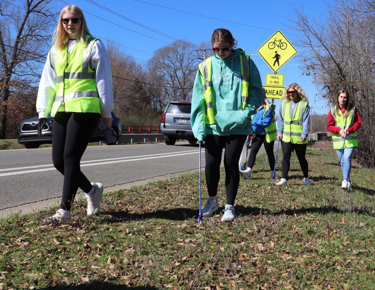 DZ sorority sisters in high visibility vests pick up litter on the side of Hogan Lane. The sorority adopted a stretch of the road several years ago and cleans it up multiple times a semester.