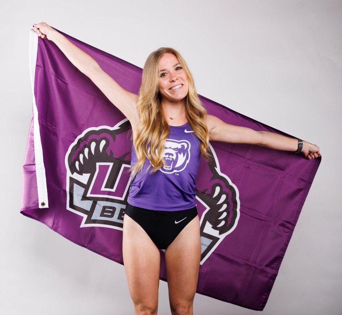 Senior Sara Steimel holds a UCA flag. Steimel broke the UCA record in the women's mile and won first place in her event, with a time of 4:51.73. At the meet UCA broke three school records.