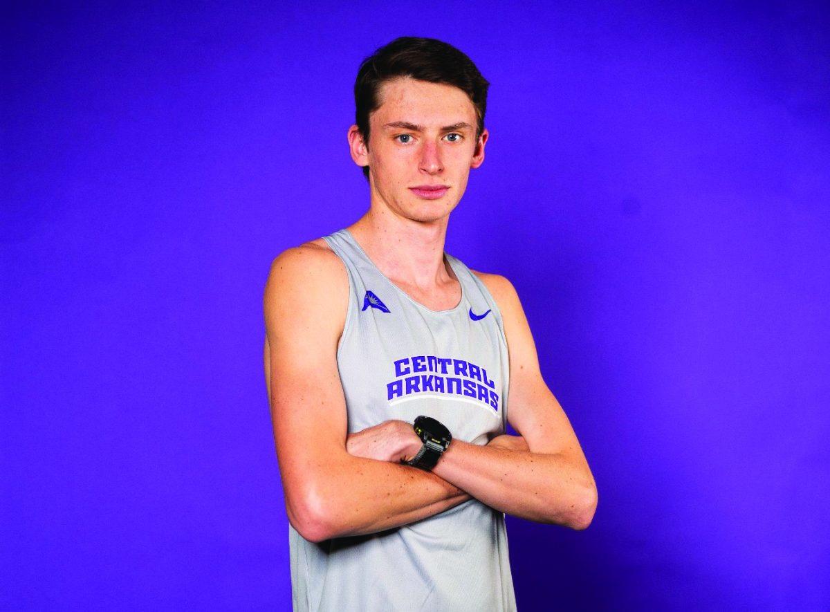 Sophomore Jack Dingman crosses his arms in front of a purple backdrop. Dingman was a member of the 2023 NCAA South Central Regional Championships team.