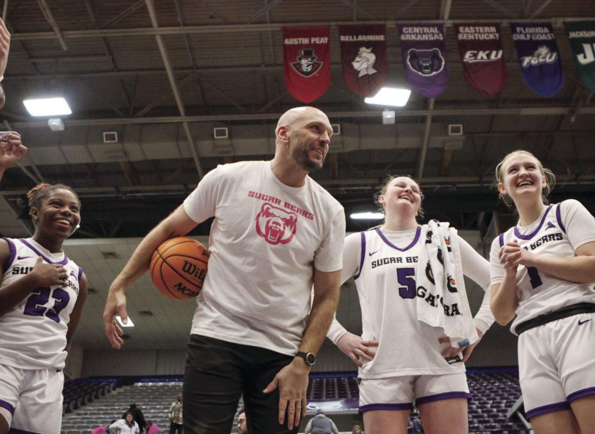 (Left) Freshman guard Kaidyn Beckwith, (center) coach Tony Kemper, (center) junior forward Bree Stephens and (right) junior guard Kinley Fisher smile together after their win. The Sugar Bears have won all 10 of their home games so far this season.