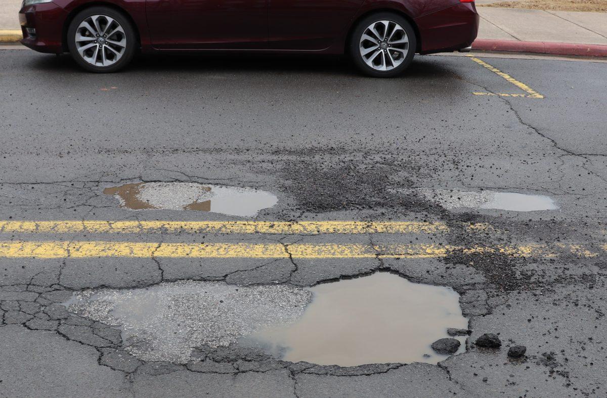 A pothole full of rainwater sits on Emma Rasor Drive in front of Snow Fine Arts on Jan. 26. The physical plant said it is working to patch all of the potholes on campus, some of which were as deep as 6-8 inches.