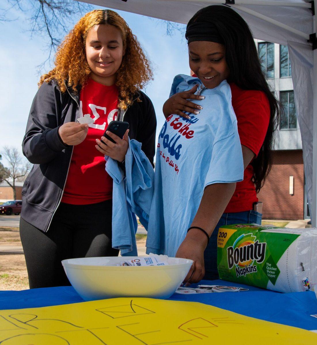 Two students look at T-shirts, buttons and stickers at one of the tables set up at Party at the Polls, hosted by SGA and Bears at the Ballot. The two groups hosted the event to get young people to vote.