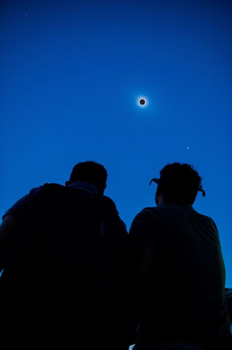 Two onlookers view the total eclipse in complete darkness.