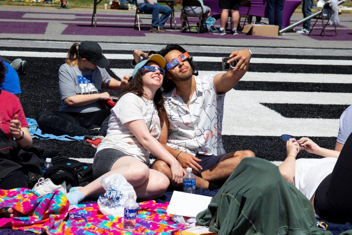 Two partygoers take a selfie on the field at Estes Stadium. The next total eclipse in Arkansas is not expected until 2045.