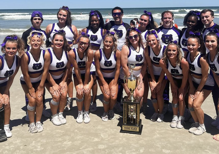  The advanced small coed team smiles behind its third place NCA College Nationals trophy.