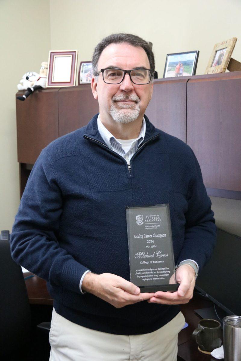 Professor Michael Cross holds his Faculty Career Champion plaque. Cross is known for his jokes in class and encouraging students. 