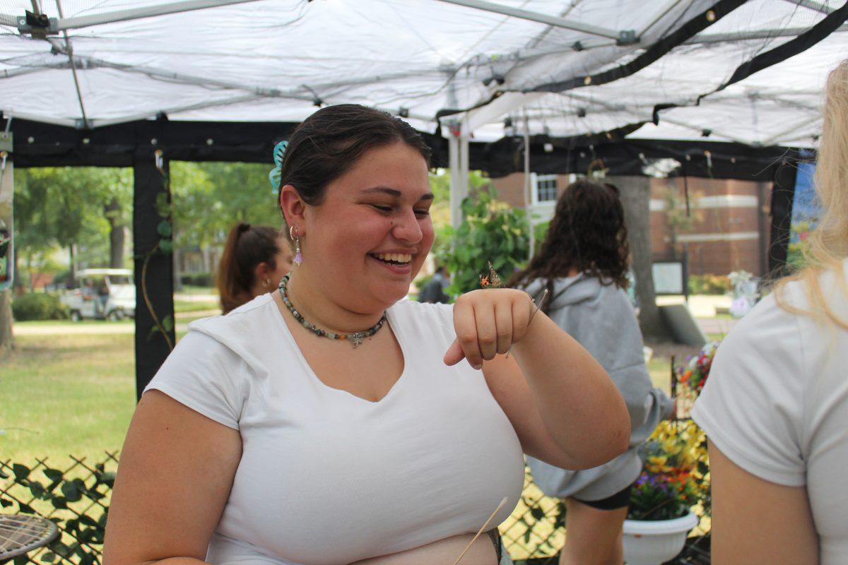 Student smiles after butterfly lands on her hand. 