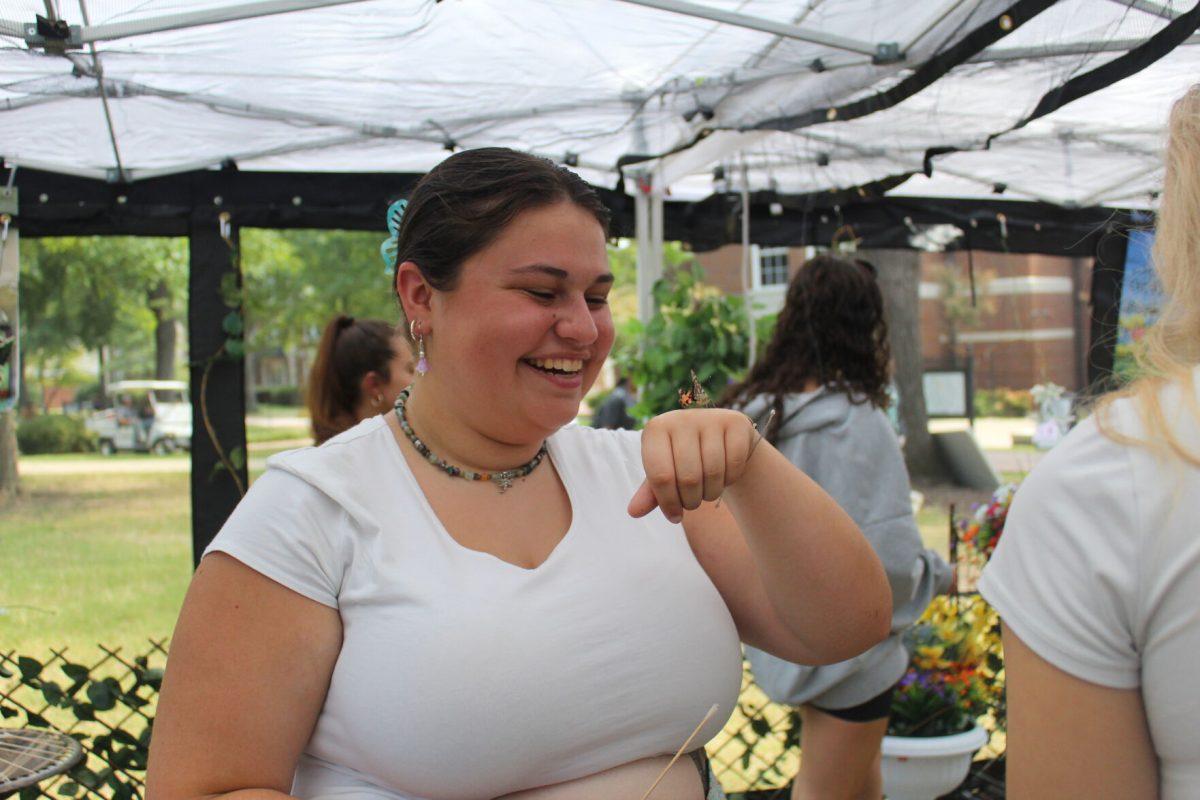 Student smiles after butterfly lands on her hand. 