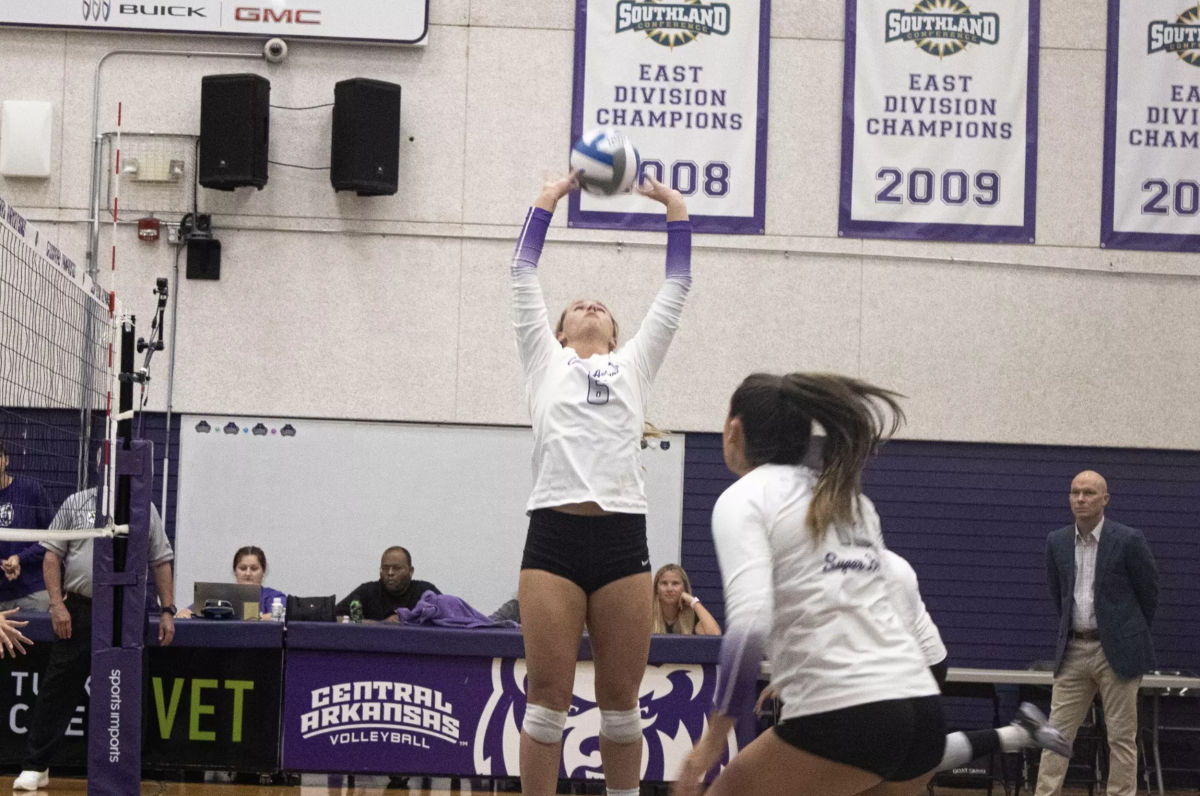 (Left) Junior setter Caylon Koons sets the ball for (right) senior middle blockerAllison Holloway. Koons totaled 34 assists in the match against Queens.