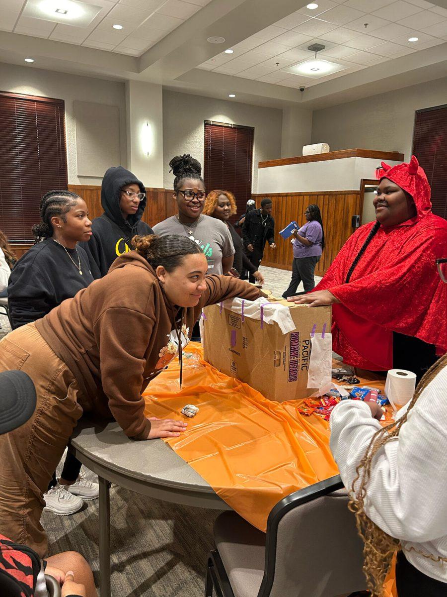 An attendee of the Halloween fest sticks her hand in the “mystery box,” which contained an unknown item.