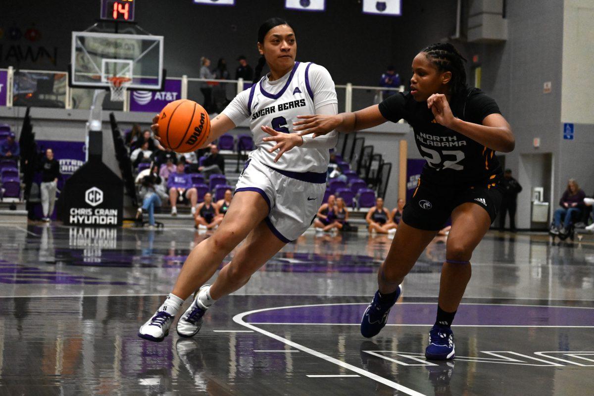 Senior guard Leah Mafua weaves past North Alabama junior guard India Howard.