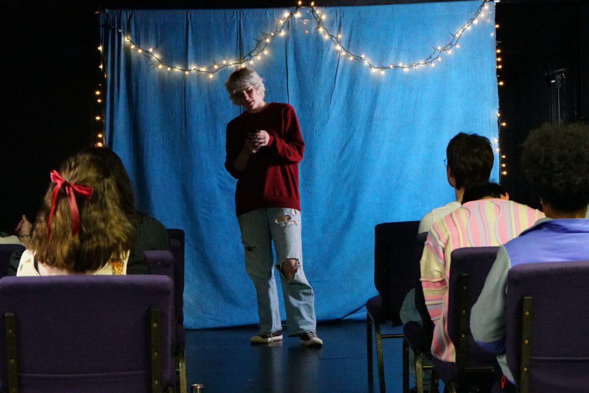A student reads poetry at an open mic night. 