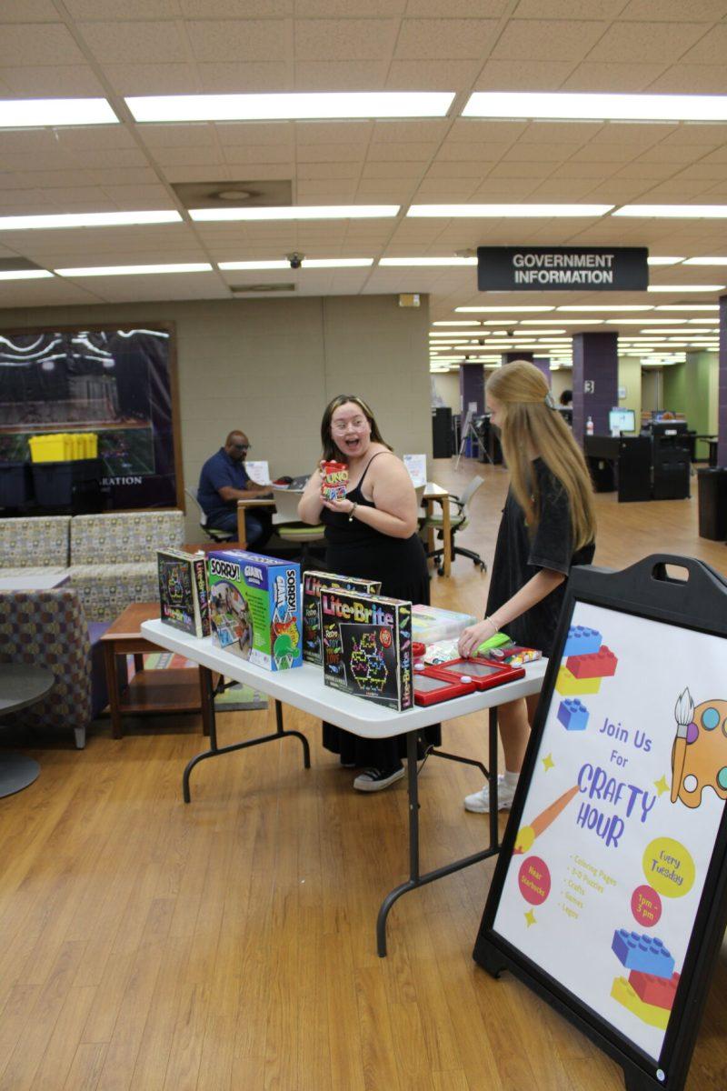 Freshman Layla Powell shows junior Avery Lindsay a deck of Uno cards. The Crafty Hour table features several games and crafts each Tuesday.