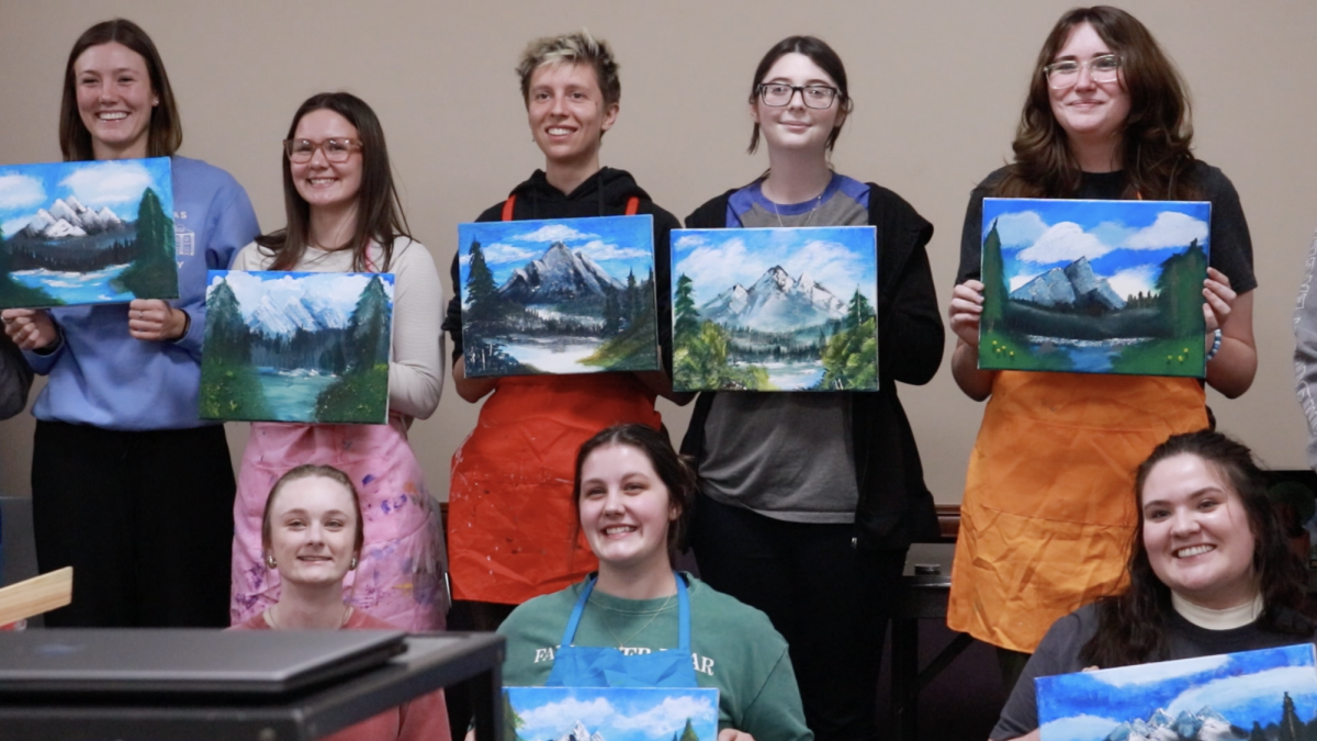 A group of attendees at 1825 Central's "Bob Ross Paint Night" pose with their final products Feb. 24. The event was the RSO's first official event. 